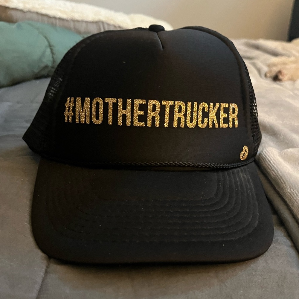 Black “#MotherTrucker” Trucker hat with gold glitter lettering